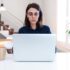 Young woman with glasses working with laptop at home. Female freelancer using computer at office.